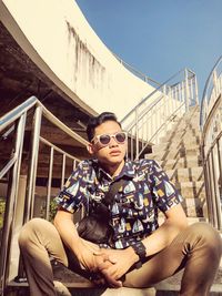 Portrait of young man sitting on railing