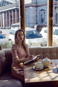 Girl in a pink dress sitting in a cafe at the table with a diary