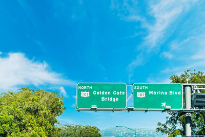 Low angle view of road sign against blue sky