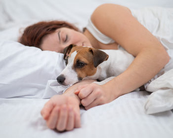 Portrait of woman with dog on bed at home