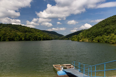 Boat sailing on river by trees against sky