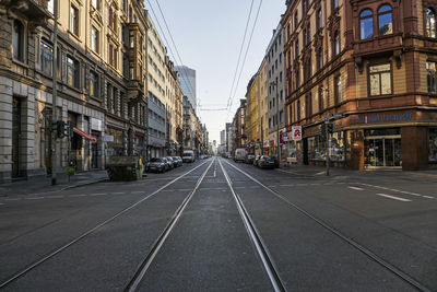 Empty road amidst buildings in city against sky