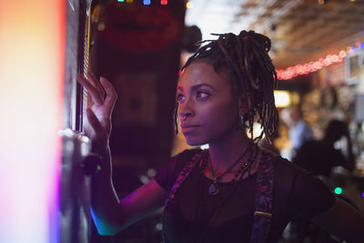 A young woman at a jukebox in a bar.