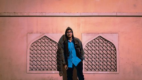 Portrait of young man standing against wall