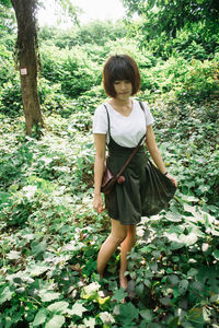 Girl standing by trees in forest