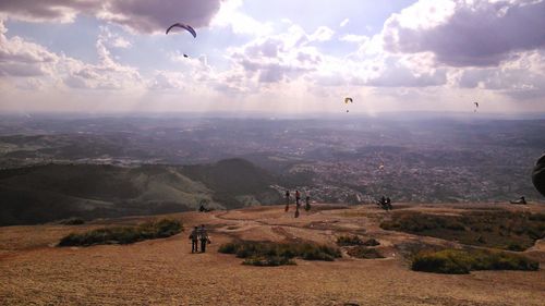 People flying over landscape against sky