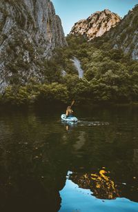 Man on rock by lake against mountain