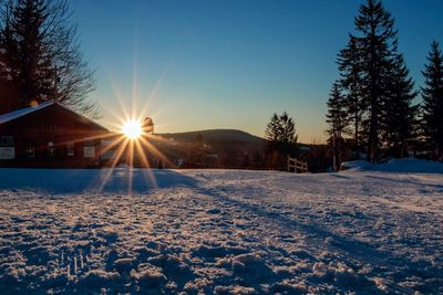 Scenic view of snow covered field against sky during sunset