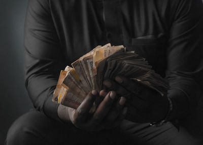 Midsection of man holding paper currencies