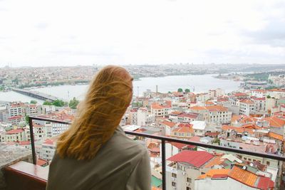 Rear view of woman looking at cityscape against sky