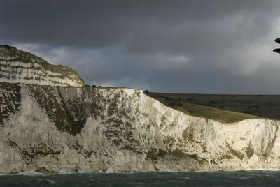 Scenic view of dover cliffs and sea against stormy clouds