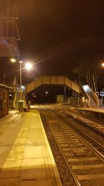 Illuminated railroad station against sky at night