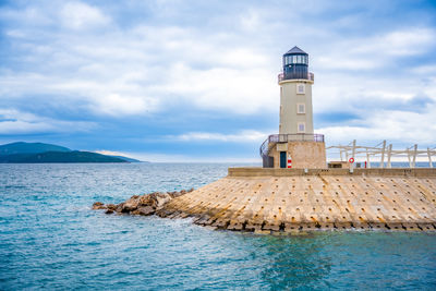 Lighthouse by sea against sky