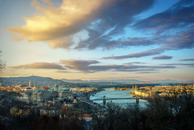 High angle view of river and buildings against sky at sunset