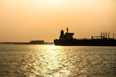 Silhouette ship in sea against clear sky during sunset