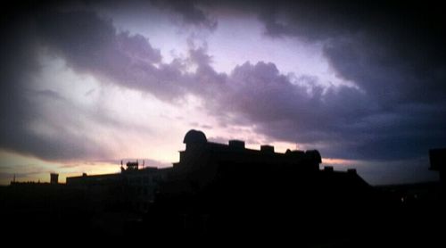 Buildings against cloudy sky at sunset