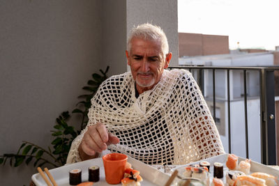 Attractive middle-aged man have fun while eating sitting at a table laid chinese  food on a terrace