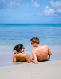 Rear view of woman swimming in sea against sky