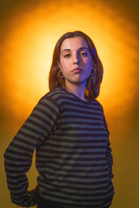 Portrait of young woman standing against yellow wall