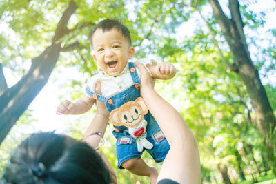 Portrait of happy boy smiling against trees