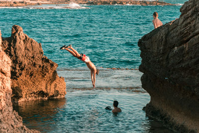 Man jumping on rock by sea