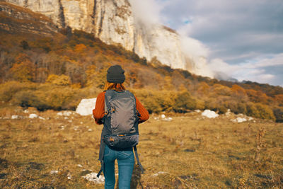 Rear view of man standing on mountain against sky