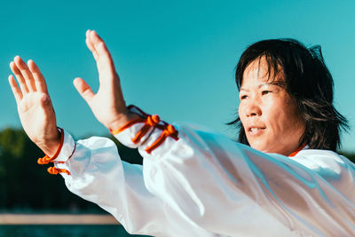 Woman practicing martial arts at lake against sky