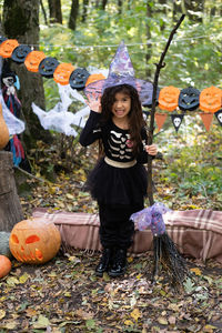 Arab girl in halloween costume and witch hat with broom in halloween decoration outdoor