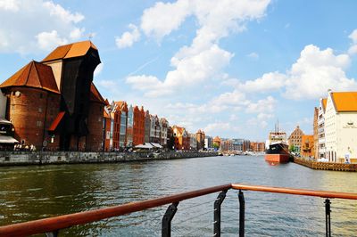 Buildings by river against sky in city