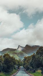 Road leading towards mountains against sky