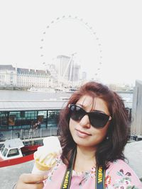 Portrait of woman with sunglasses against sky in city