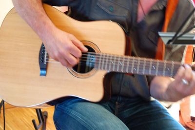 Midsection of man playing guitar