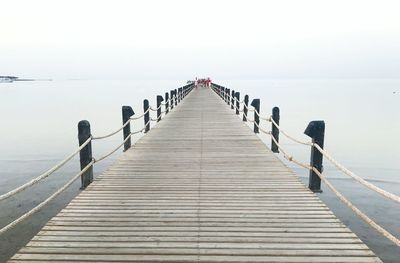 Wooden pier on sea against clear sky