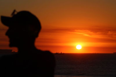 Silhouette man on beach against sky during sunset