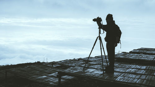 Man photographing at camera against sky
