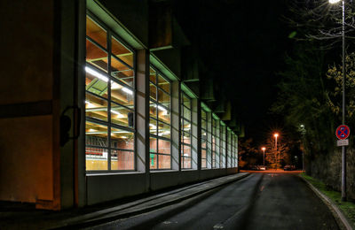 Road by illuminated building at night