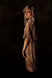 Young woman with eyes closed standing against black background