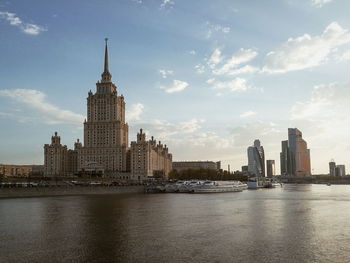 City at waterfront against cloudy sky