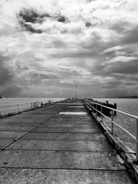 Empty pier over sea against sky