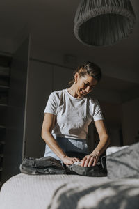 Woman folding clothes in bedroom