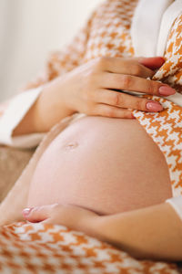 Midsection of woman sitting on bed