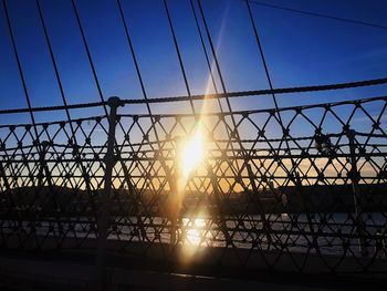 Silhouette fence against sky during sunset