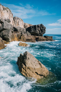 Scenic view of sea by cliff against blue sky