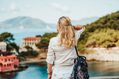 Rear view of woman standing by mountain against sky