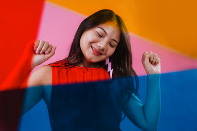 Portrait of young woman standing against yellow background