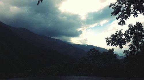 Silhouette of mountain range against cloudy sky