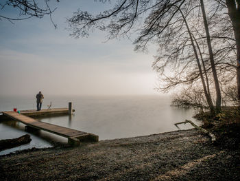 Full length of man standing on pier by sea against sky