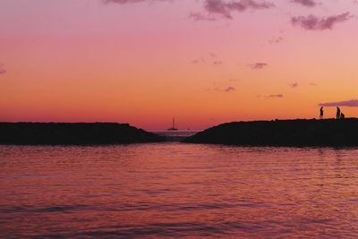 Silhouette of sailboat in sea during sunset