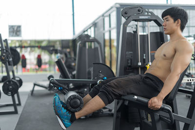 Side view of shirtless man exercising in gym