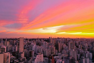 Aerial view of city against dramatic sky during sunset